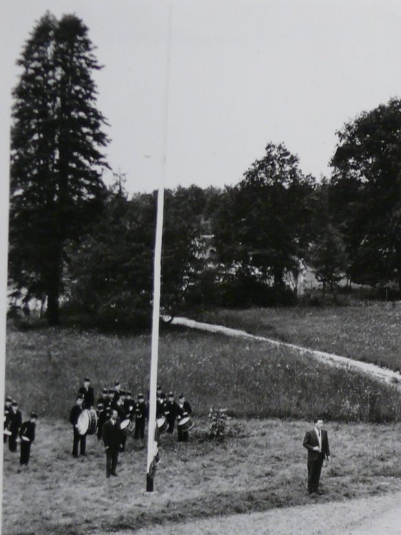 Il s'agit d'une photographie d'un album photo. On retrouve trois photos dans l'album. Il y a des jeunes adolescents autour d'un drapeau, puis sur la dernière photo, les adolescents sont rangés.